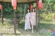 A couple of women standing next to each other under red lanterns.