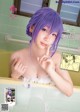 A woman with purple hair is taking a bath in a tub.