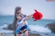 A woman holding a red stuffed animal on a beach.