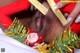 A black woman in a santa claus outfit is opening a gift box.