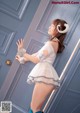 A woman in a white dress and blue stockings posing in front of a door.