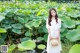 A woman in a white dress standing in a pond of lotus flowers.